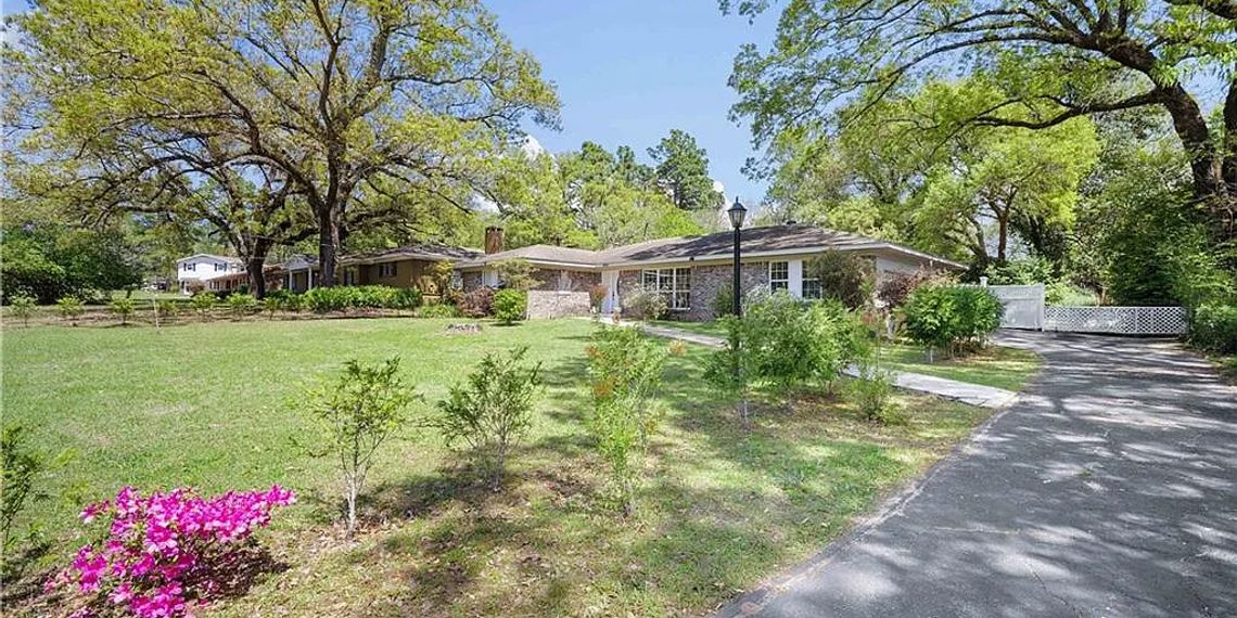 Brick home with an attached two-car garage on a tree-lined lot at 1054 Matterhorn St, Mobile, Alabama
